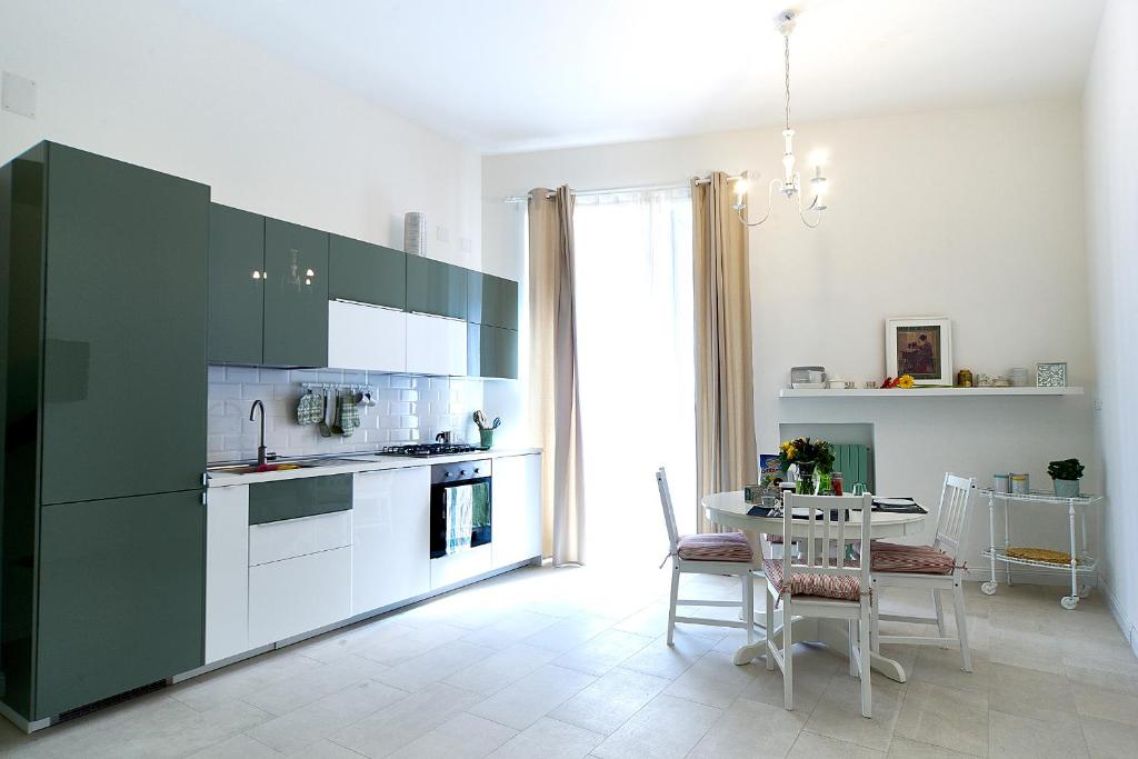 ナポリにあるla marcellinaのキッチン(緑のキャビネット、テーブル、椅子付)