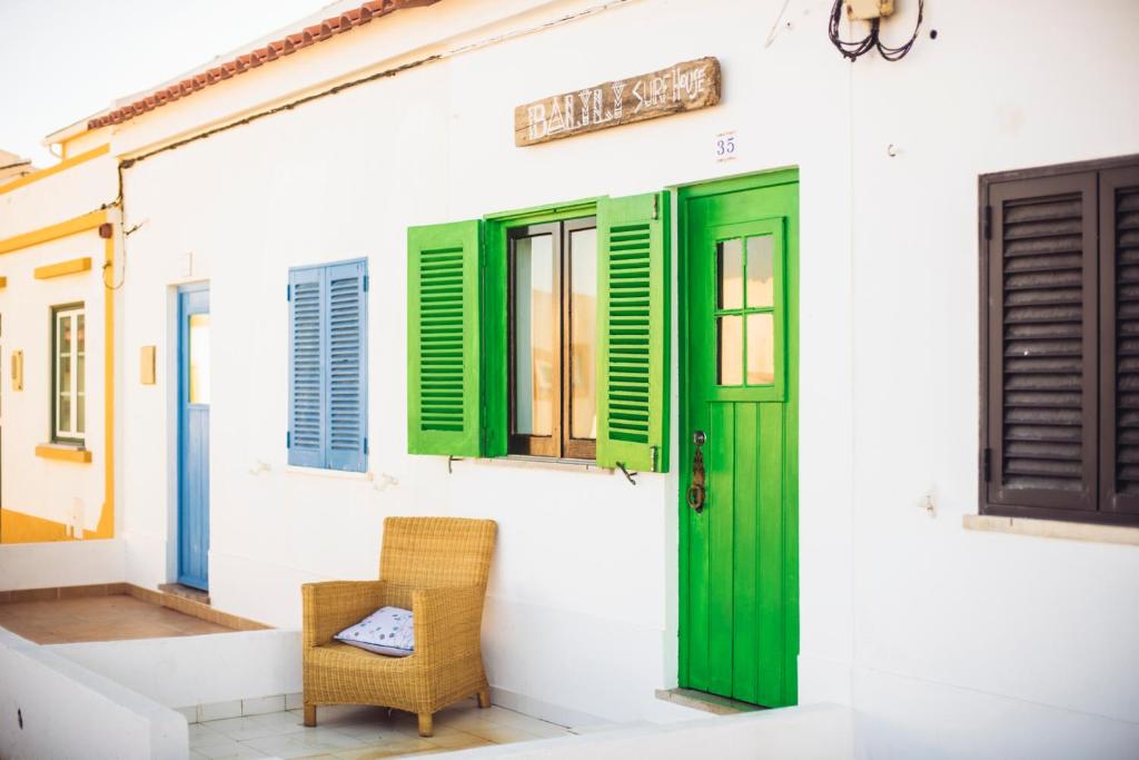 a house with green shutters and a chair at Balili Surf House in Baleal