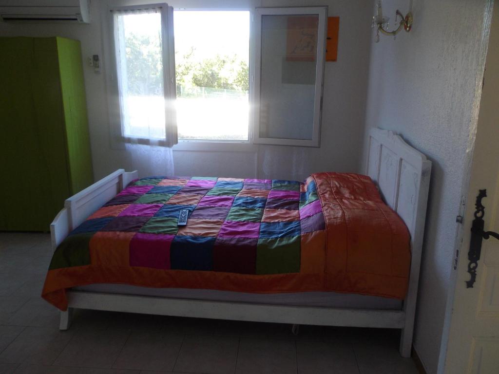 a bedroom with a bed with a colorful quilt on it at auberge des garrigues in Nîmes