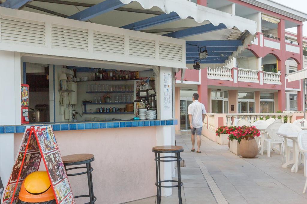 a man walking past a restaurant with tables and chairs at Résidence Pierre & Vacances l'Ange Gardien in Villefranche-sur-Mer