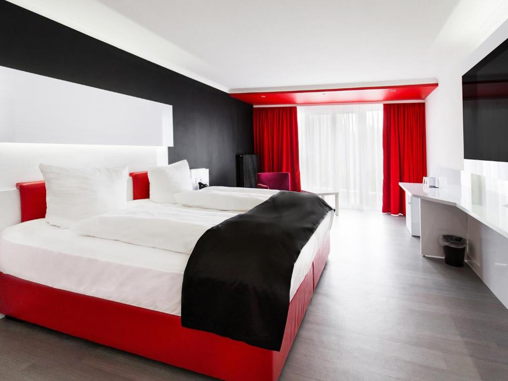 sypialnia z czerwono-białym łóżkiem i biurkiem w obiekcie DORMERO Hotel Freudenstadt w mieście Freudenstadt