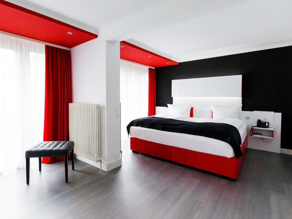 a bedroom with a large bed and a large window at DORMERO Hotel Freudenstadt in Freudenstadt