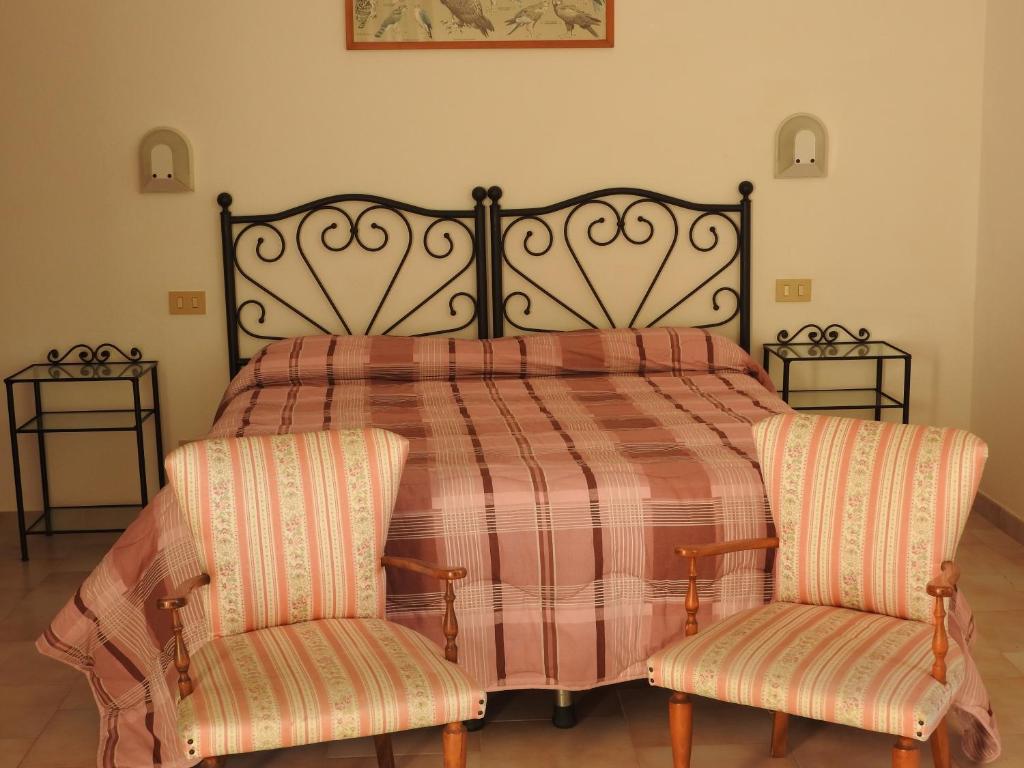 a bedroom with a bed and two chairs at Agriturismo Villa Caprareccia in Bibbona
