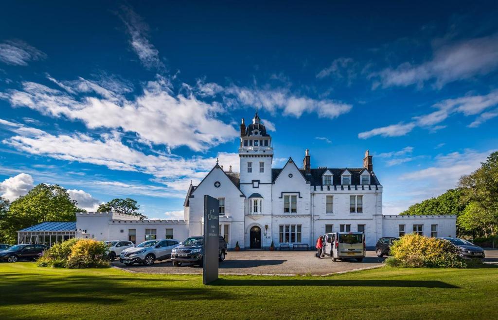 un gran edificio blanco con una torre en la parte superior en Skeabost House Hotel, en Portree