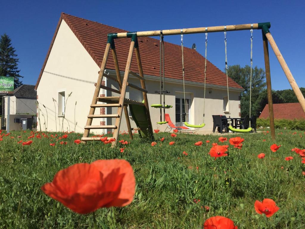 a swing in a field of flowers with a house at Gîte de Roches Hibou in Seigy