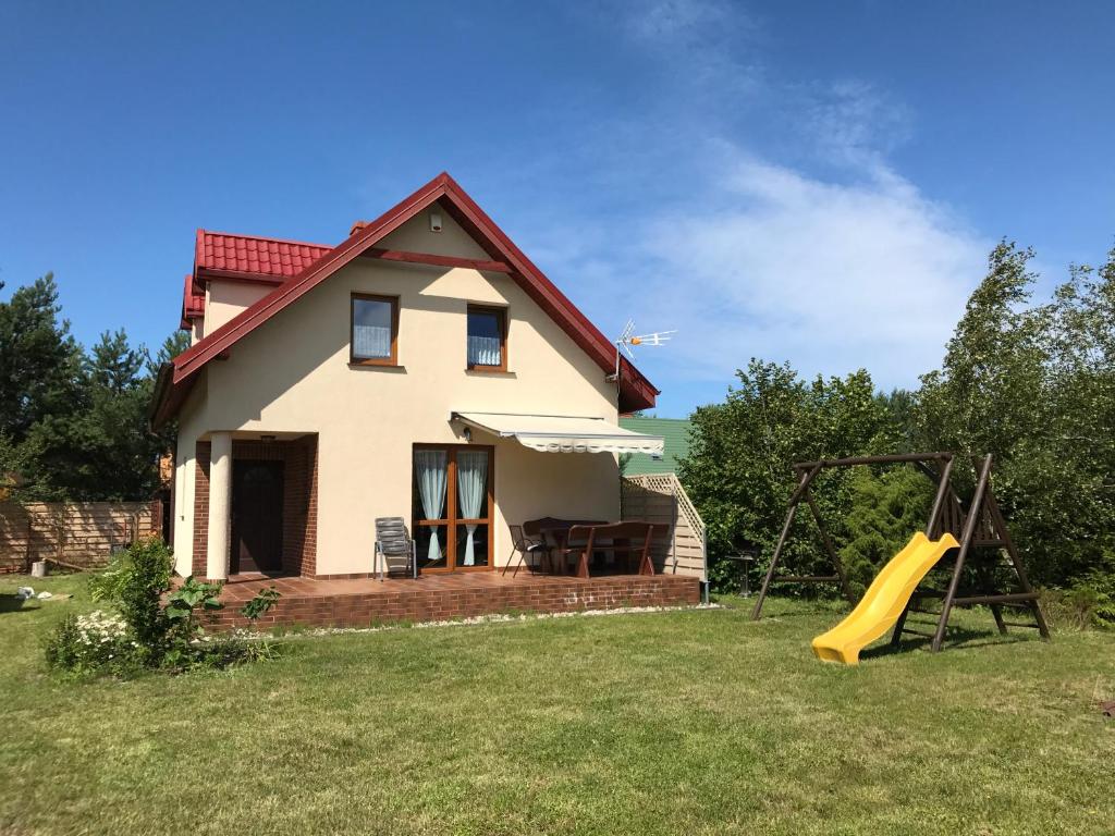 a house with a slide and a playground at Domek u Danusi in Lubiatowo