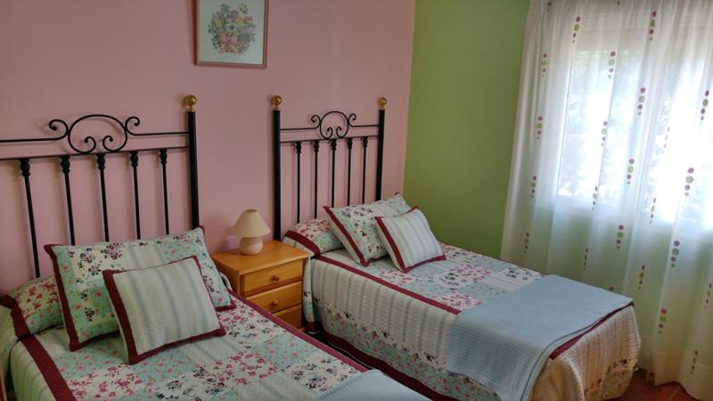 a bedroom with two twin beds and a window at Apartamentos La Flor in San Martín de Moncayo