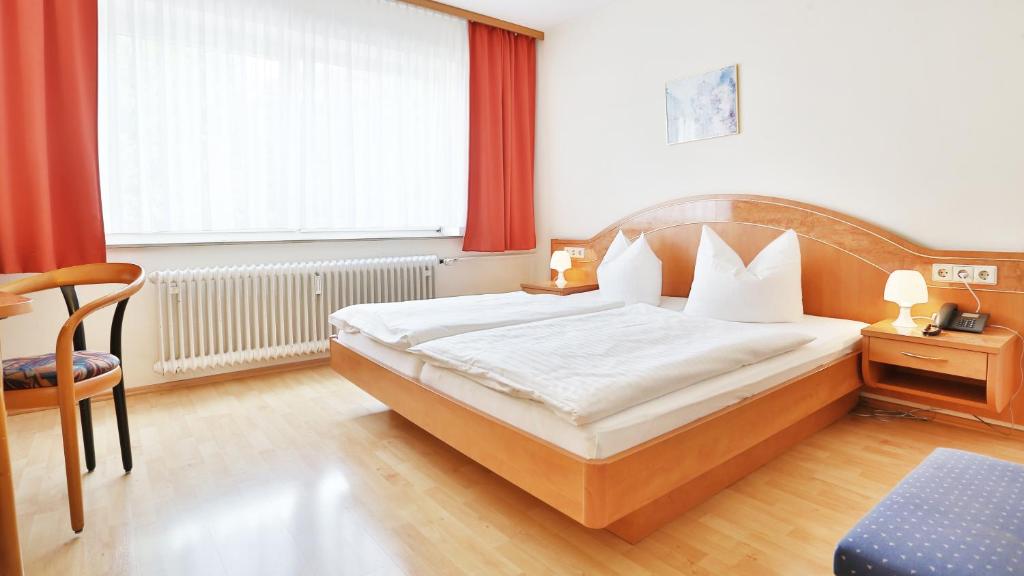 a bedroom with a bed and a chair and a window at Hotel Europa in Pforzheim