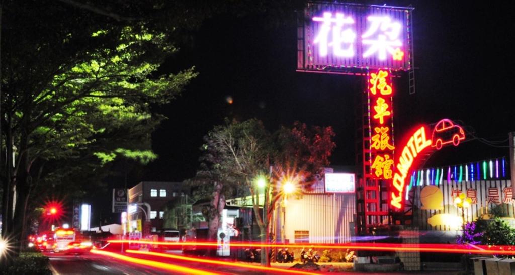 una calle de la ciudad por la noche con un cartel de neón en Flower Motel, en Chiayi