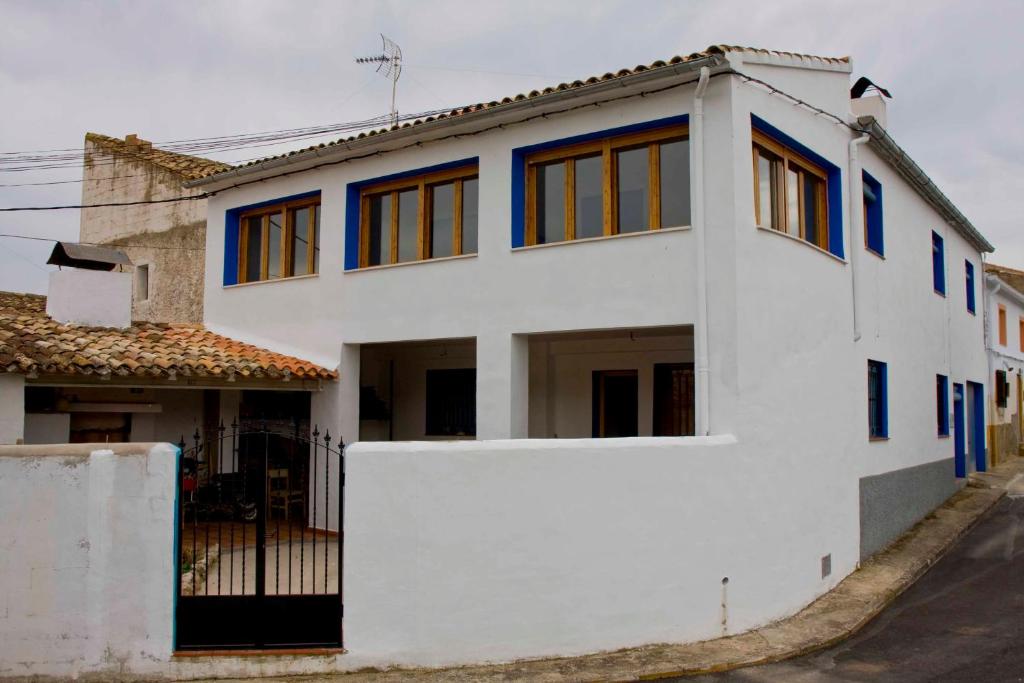 een wit huis met blauwe ramen op een straat bij El mirador del norte in Cortez de Pallas