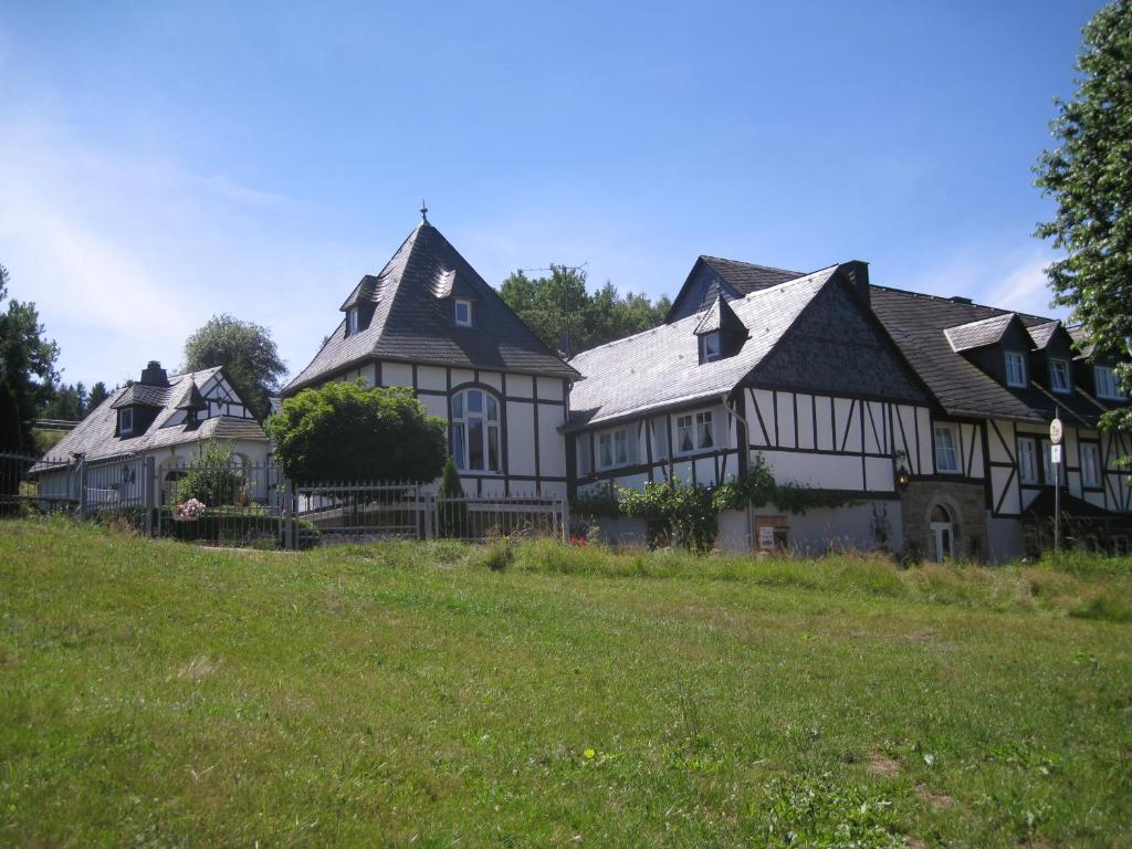 ein großes weißes und schwarzes Haus auf einem grünen Feld in der Unterkunft Romantikmühle Heartlandranch in Krummenau