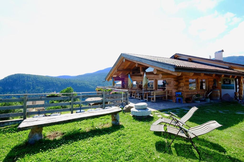 a log cabin with a bench and chairs in the grass at Agriturismo Reinhof in San Felice