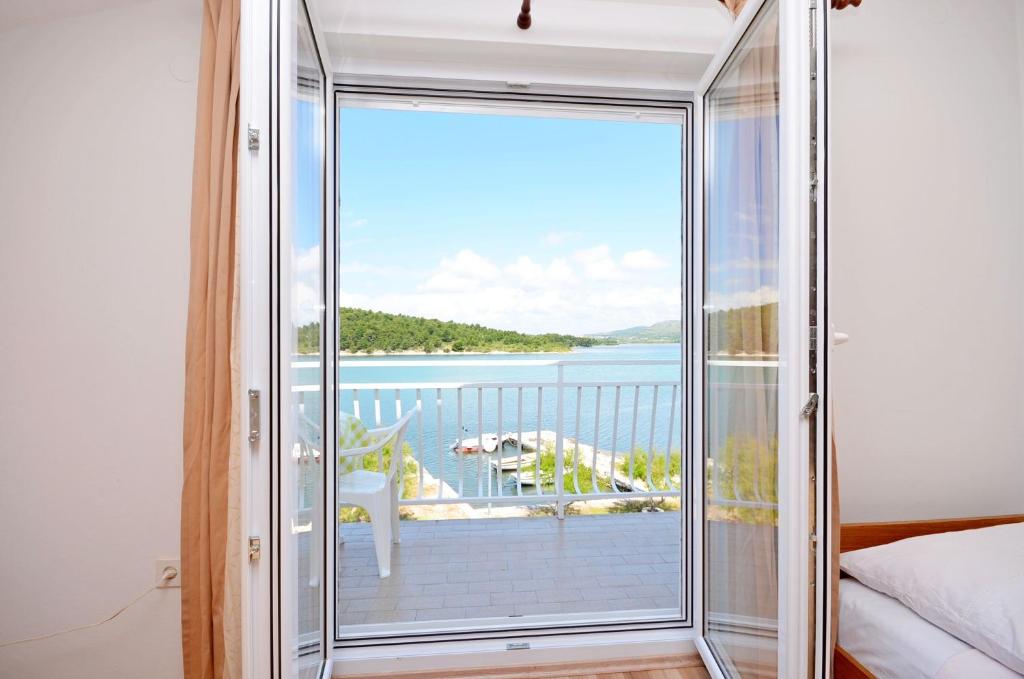 a bedroom with a large glass door leading to a balcony at Apartments Vila Punta in Jadrtovac