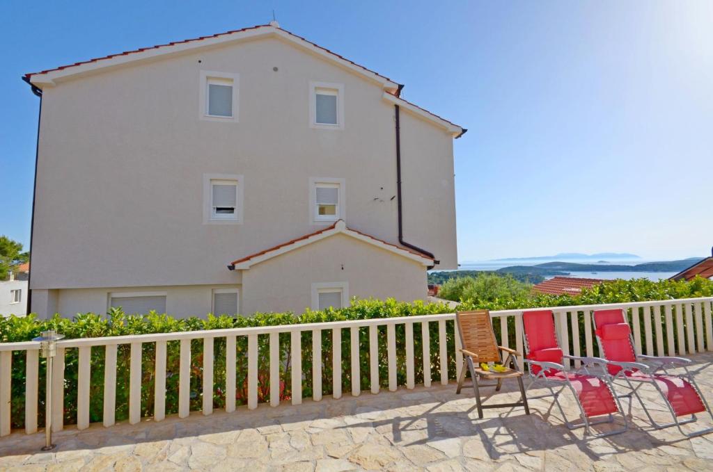 a white building with chairs and a fence at Apartments Marija in Hvar