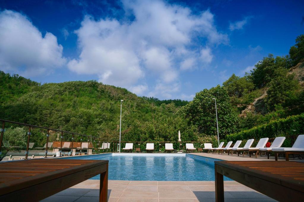 una piscina con tumbonas y una montaña en Agriturismo Cascina del Vai, en Cairo Montenotte