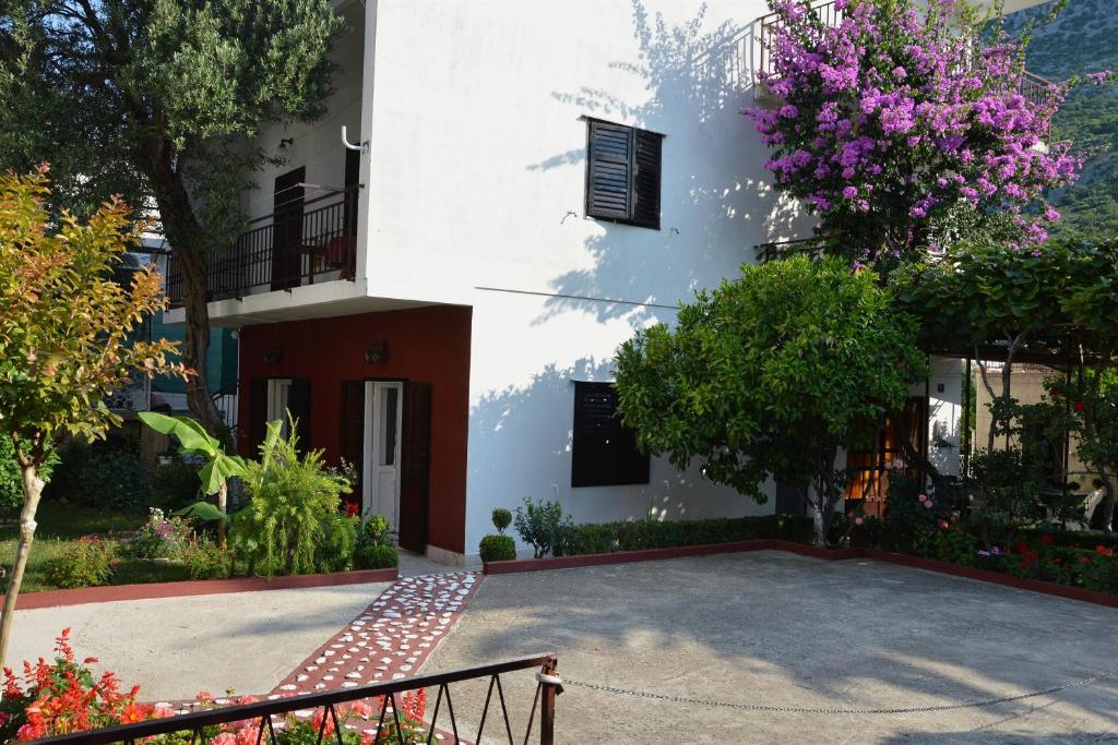 a white building with a tree with purple flowers at Apartment and Rooms Danica in Podaca