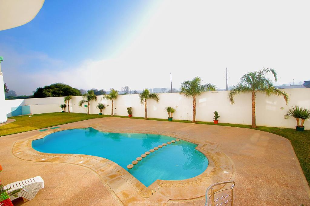 ein Schwimmbad in der Mitte eines Gartens in der Unterkunft Hotel LA PALOMA in Tétouan