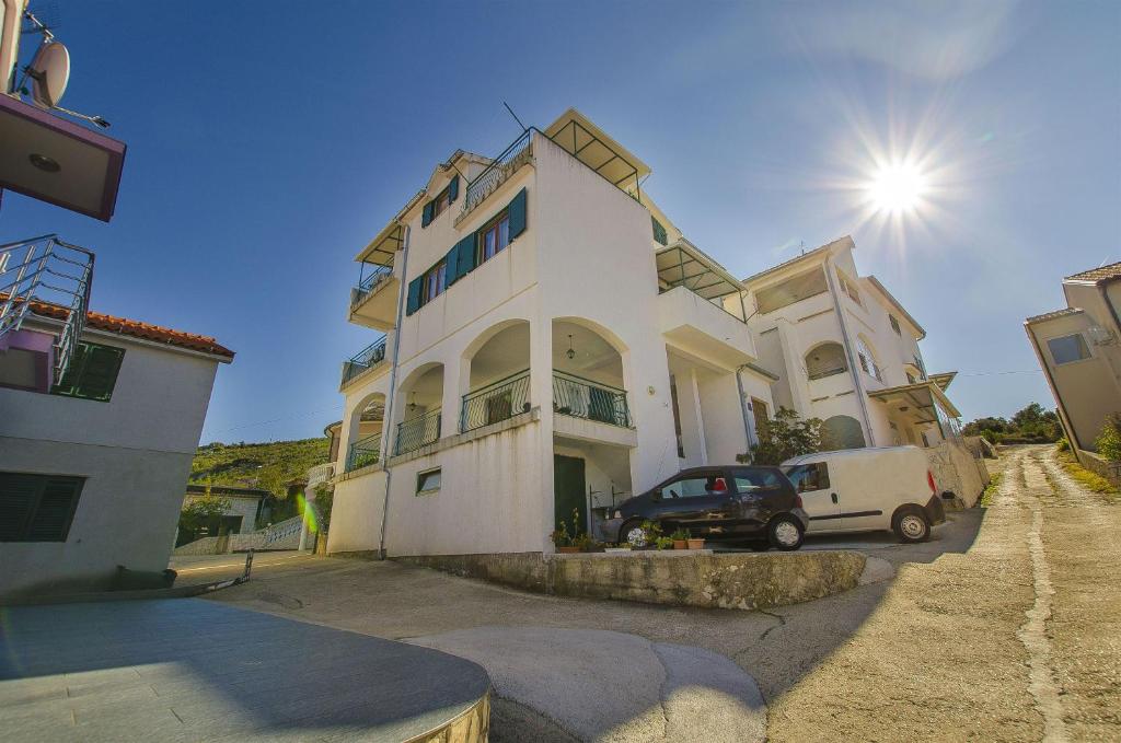 a white house with a car parked in front of it at Apartments Toni in Primošten