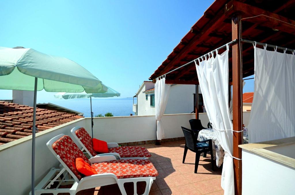 een patio met stoelen en een parasol op een dak bij Apartments Katica in Trogir