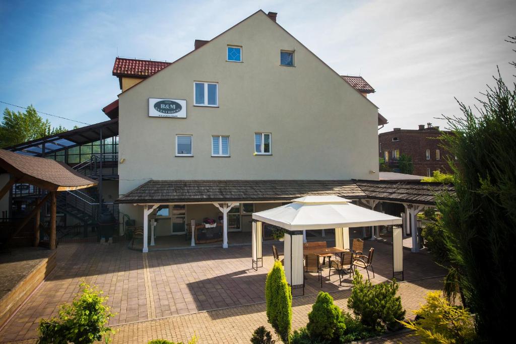 un gran edificio con un patio y una sombrilla blanca en B&M Guesthouse en Oświęcim