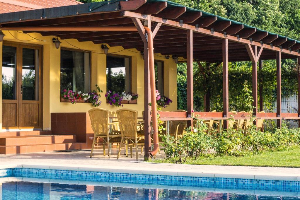 a pavilion with chairs and a table next to a pool at Vila Maria Snagov in Snagov