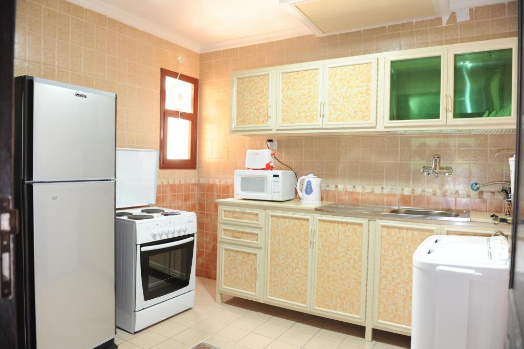 a kitchen with a white refrigerator and a stove at Terrace Furnished Apartments- Salmiya in Kuwait