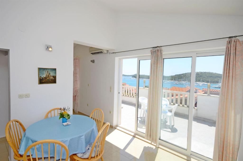 a dining room with a table and a balcony at Apartments Branislav in Rogoznica