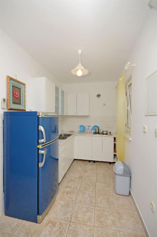 a large kitchen with a blue refrigerator in it at Apartments Branislav in Rogoznica