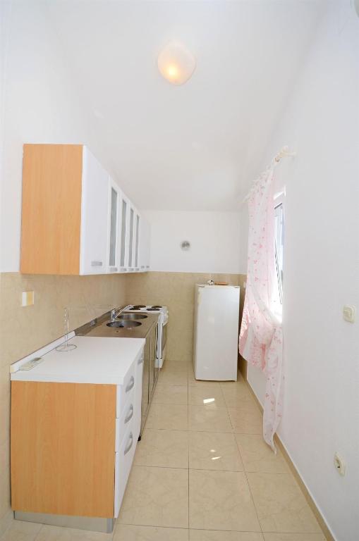 a kitchen with white cabinets and a white refrigerator at Apartments Branislav in Rogoznica