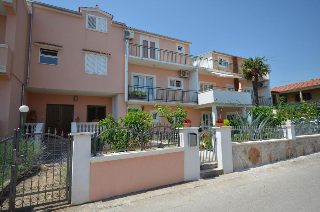 un immeuble d'appartements avec une clôture devant lui dans l'établissement Apartments and Room Zinka, à Vodice