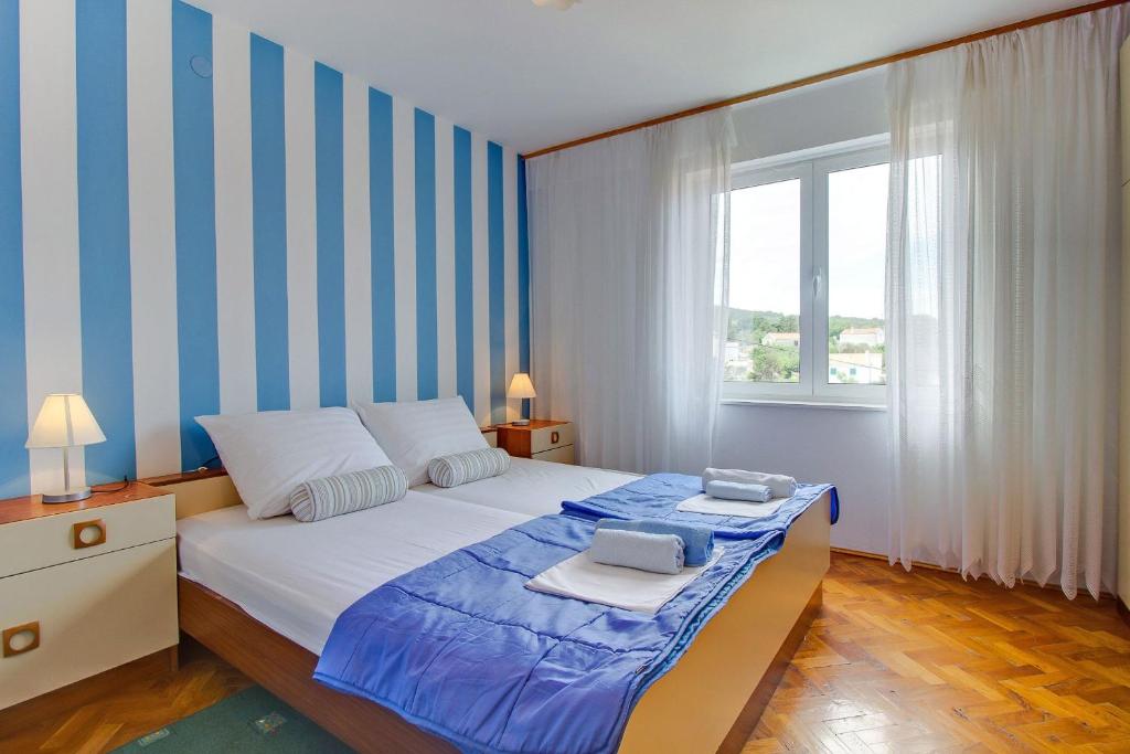 a bedroom with a bed with blue and white stripes at Room Milka in Veli Lošinj