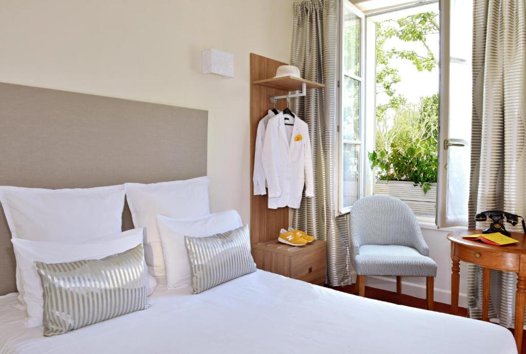 een slaapkamer met een wit bed, een stoel en een raam bij Cit'Hôtel Le Plantagenet in Chinon