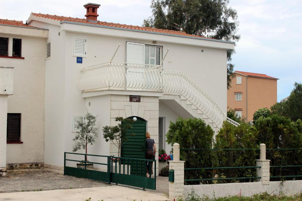 a person standing in the doorway of a white house at Apartments Berislav in Rogoznica