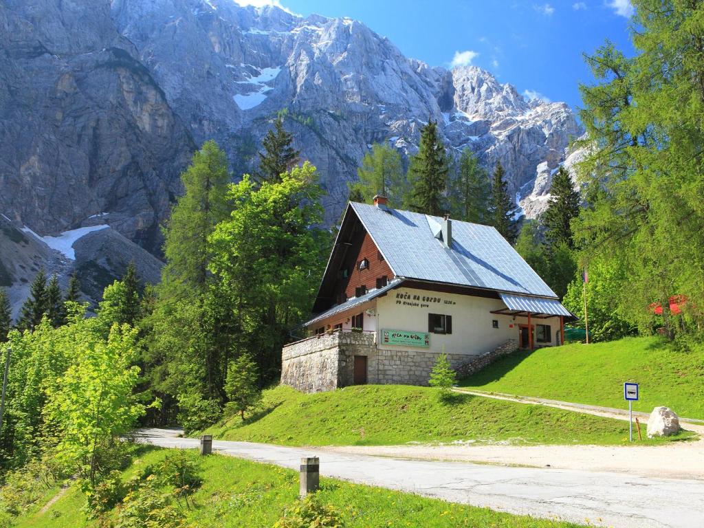 a house on a hill with mountains in the background at PLANINSKA KOČA NA GOZDU in Kranjska Gora