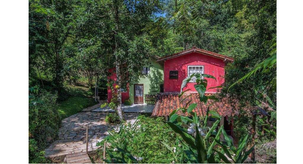 une maison rouge au milieu d'un jardin dans l'établissement Ytororô O som das águas, à Parati