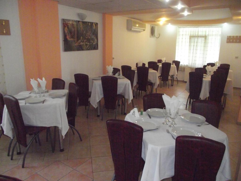 クラヨーヴァにあるVilla Flormangのテーブルと椅子(白いテーブルクロス付)が備わる客室です。