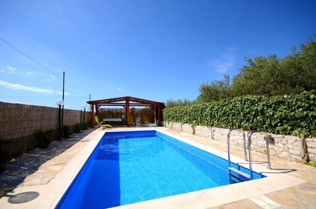 a swimming pool with a gazebo in a yard at Apartments Mirko in Seget Vranjica