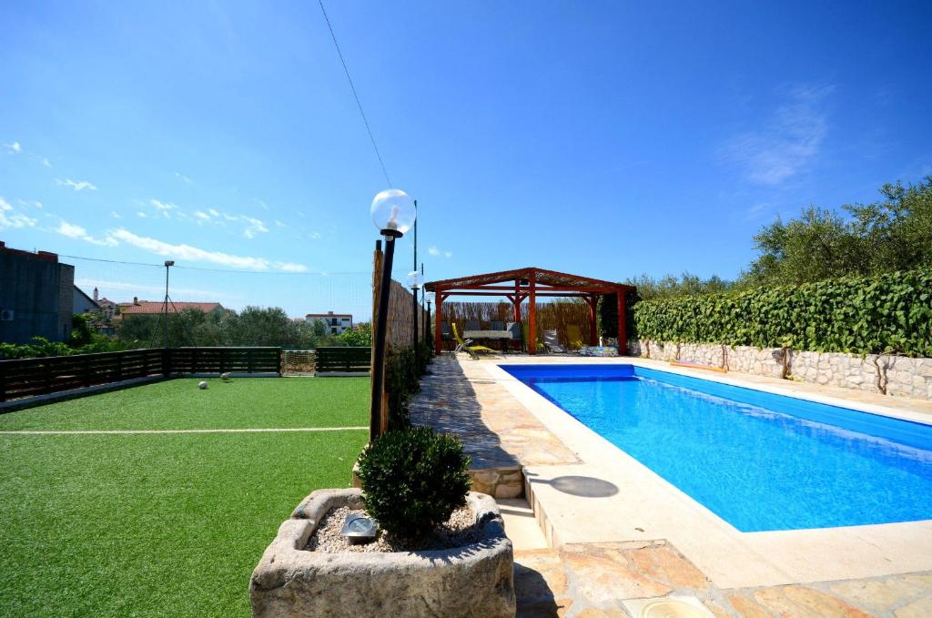 a pool with a gazebo next to a yard at Apartments Mirko in Seget Vranjica