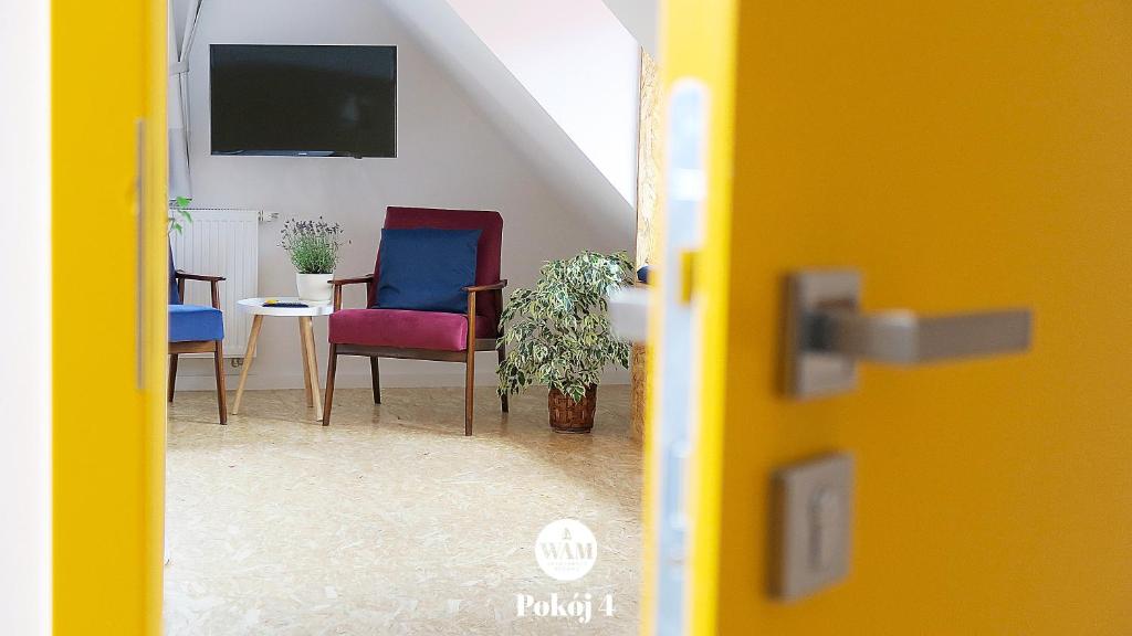 a door open to a living room with chairs and a tv at WAM Rooms in Giżycko
