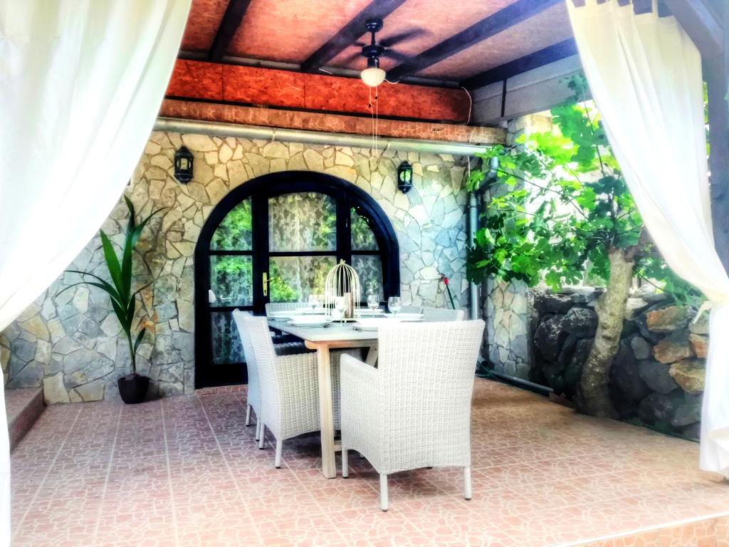 a patio with a table and chairs and a stone wall at Holiday House Little Precious in Sveti Anton