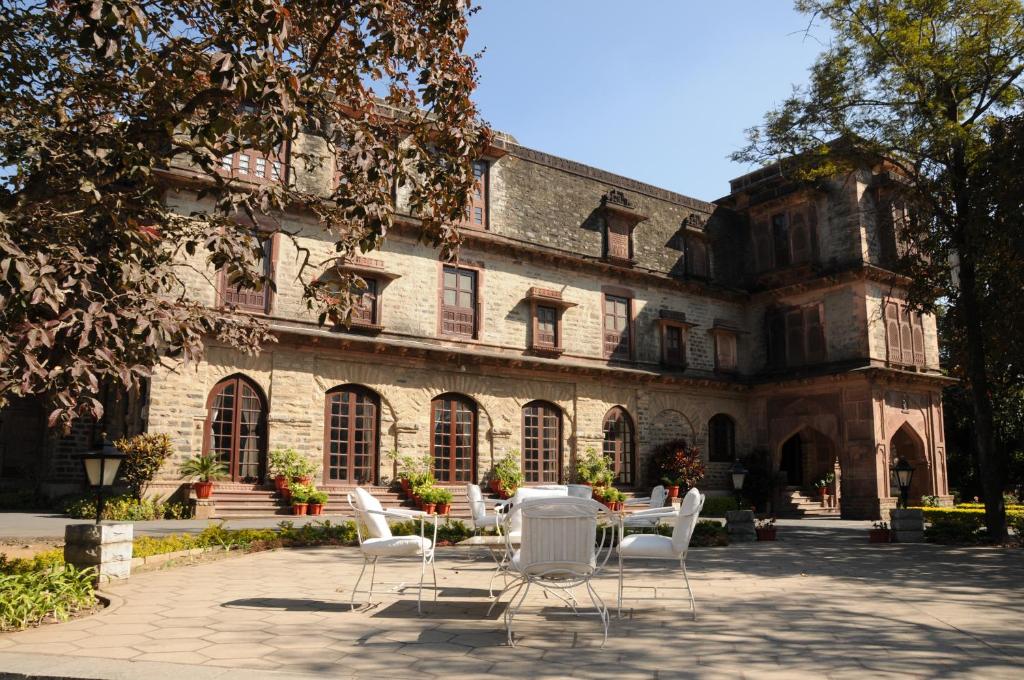 einer Gruppe von Stühlen und einem Tisch vor einem Gebäude in der Unterkunft Palace Hotel - Bikaner House in Mount Ābu