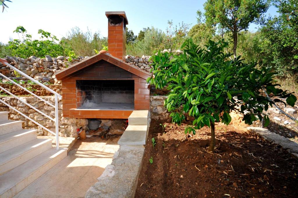 a brick oven in a garden with a tree at Apartments Val in Vinišće