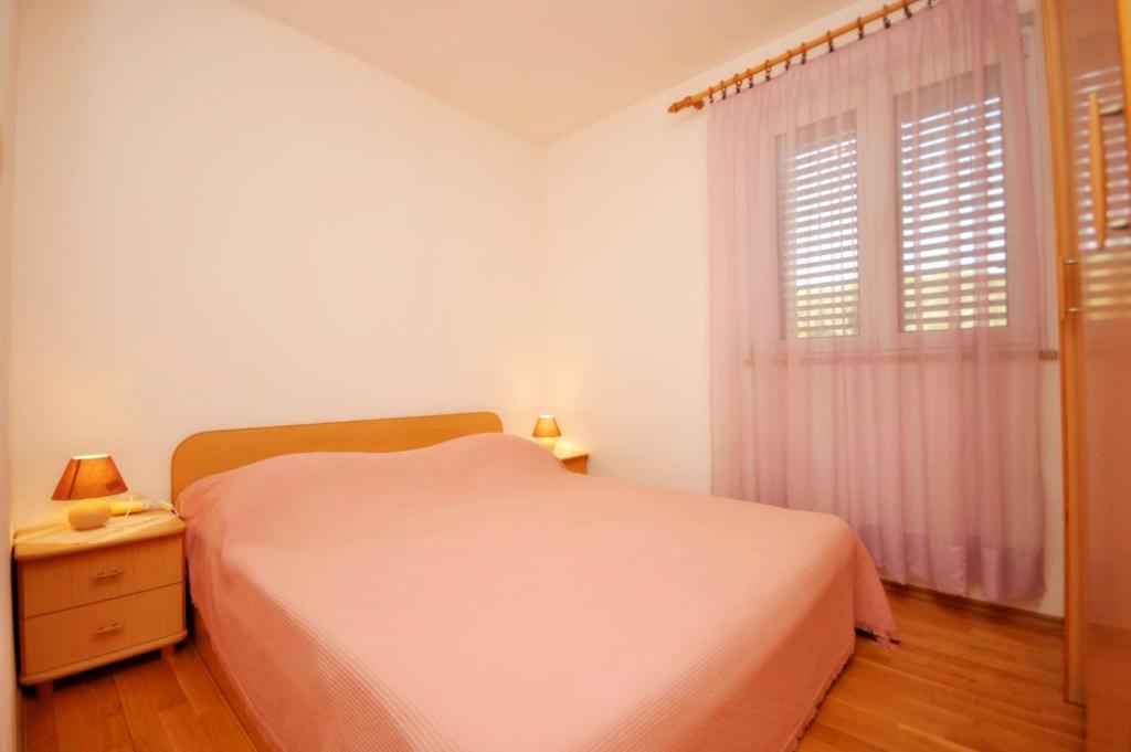 a white bedroom with a bed and a window at Apartments Val in Vinišće