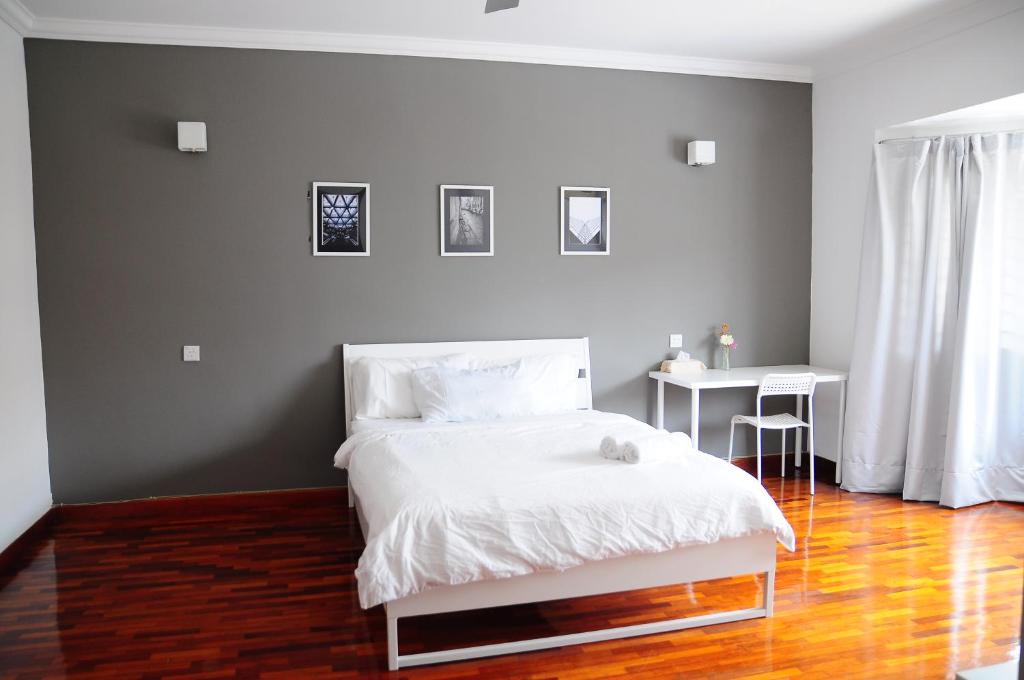 1 dormitorio con cama blanca y mesa en GRAYHAUS Guest House, en Petaling Jaya