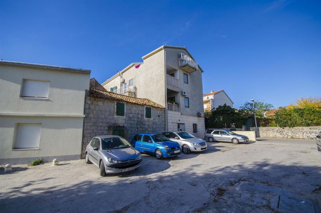 un grupo de autos estacionados en un estacionamiento al lado de un edificio en Apartments Mijo, en Kaštela