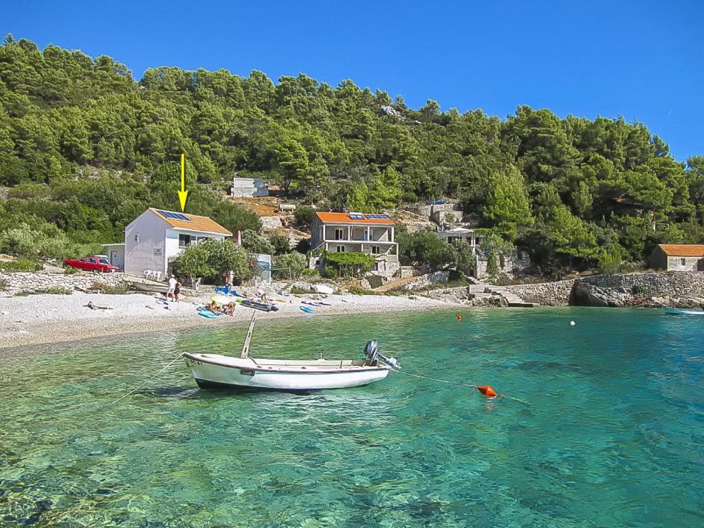 a boat sitting in the water on a beach at Apartments Robinzon Petar in Gdinj