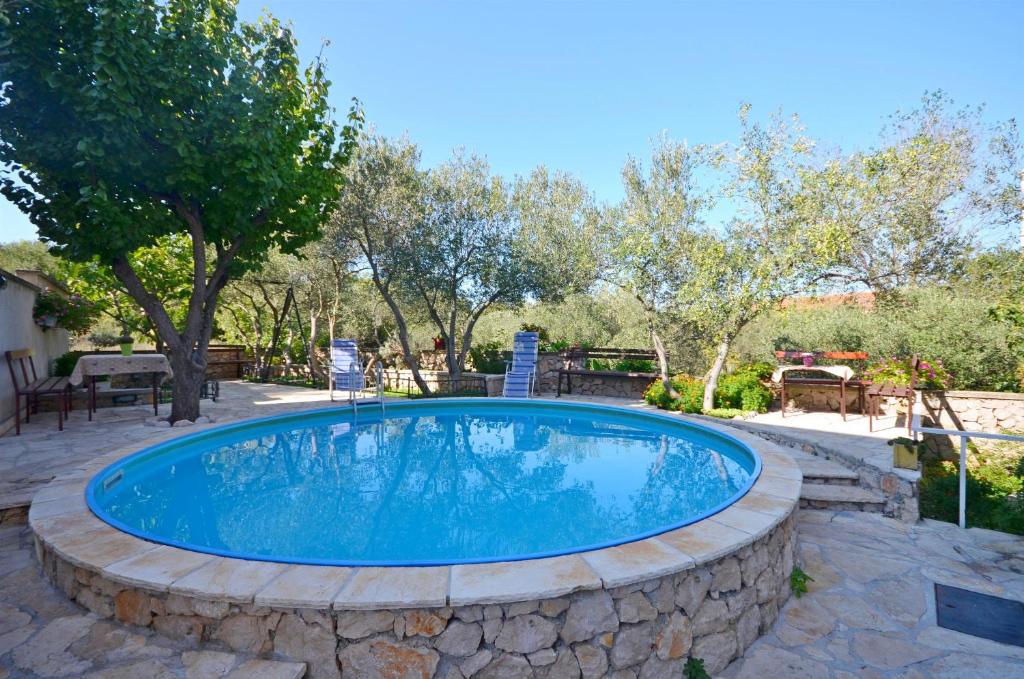 a large pool with a stone wall around it at Apartment Gordan in Murter