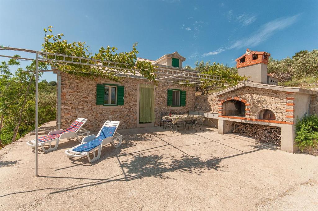 ein Haus mit einer Terrasse mit Stühlen und einem Kamin in der Unterkunft House Vela Lozna in Postira