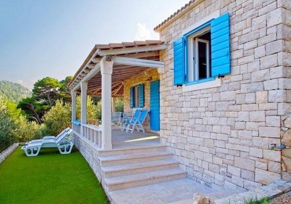 a brick house with a blue window and a patio at House Nevena in Postira