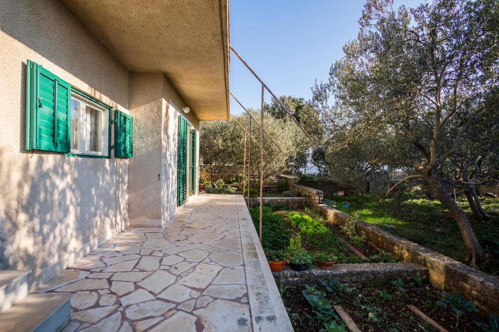 a walkway next to a building with green shutters at Apartment Srecko in Vinišće